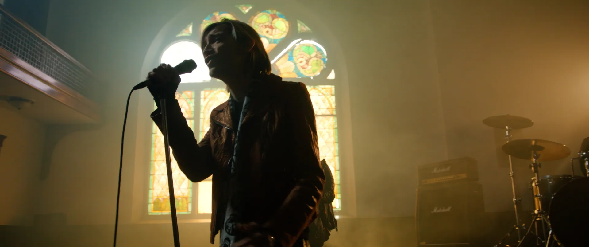 Alex Band singing into the mic, backlit gold